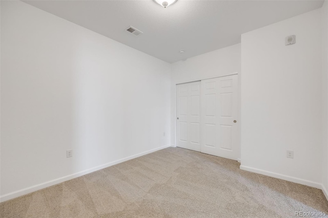 unfurnished bedroom with a closet and light carpet