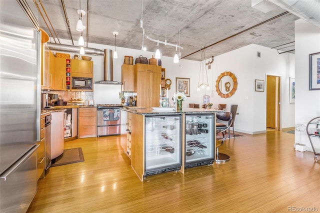 1401 Wewatta St Unit 806, Denver, CO 80202 - kitchen featuring built in appliances, wall chimney exhaust hood, light wood finished floors, and a kitchen island