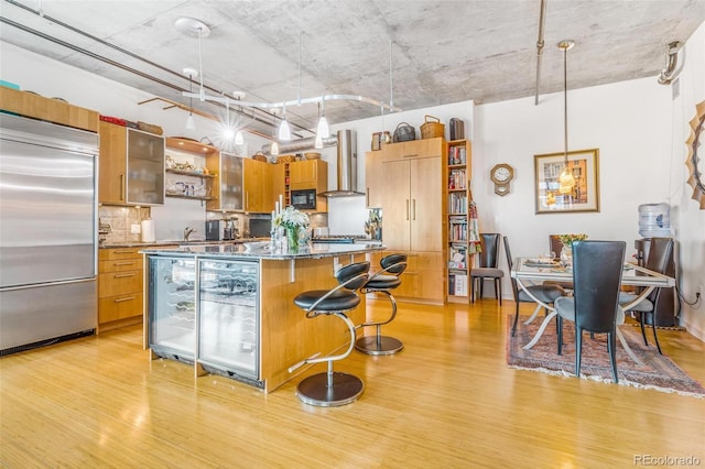 1401 Wewatta St Unit 806, Denver, CO 80202 - kitchen with built in refrigerator, open shelves, wall chimney exhaust hood, and light wood finished floors