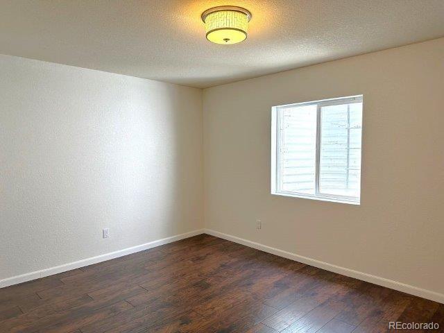 15594 E 97th Ave, Commerce City, CO 80022 - empty room with dark wood-style floors and baseboards