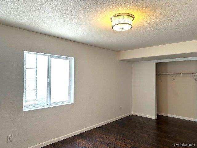 15594 E 97th Ave, Commerce City, CO 80022 - unfurnished bedroom with dark wood-type flooring, a closet, and a textured ceiling