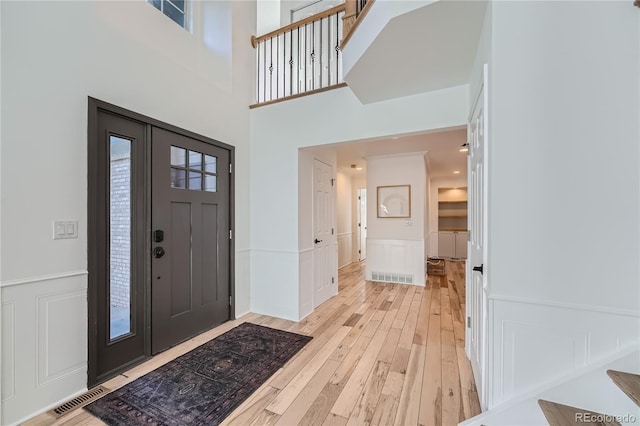 entrance foyer with a towering ceiling and light wood-type flooring