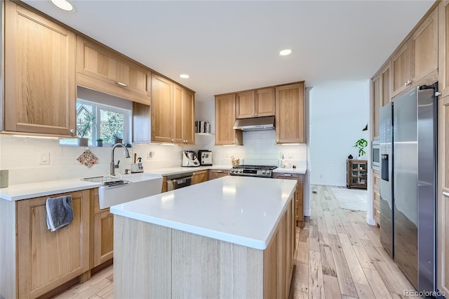 kitchen with sink, light wood-type flooring, backsplash, a center island, and stainless steel appliances