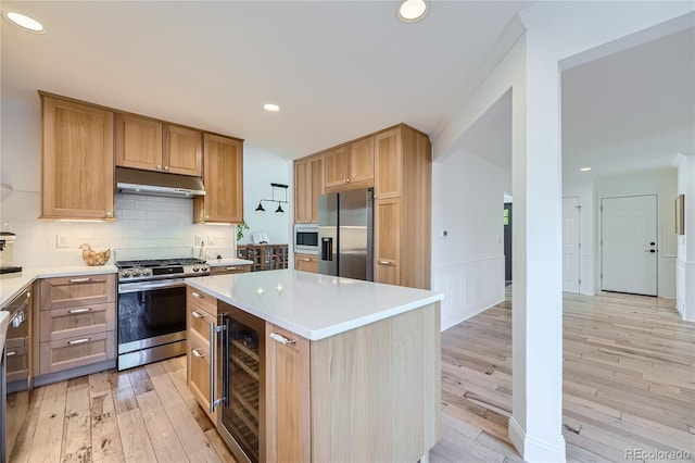 kitchen with wine cooler, backsplash, appliances with stainless steel finishes, a kitchen island, and light hardwood / wood-style flooring