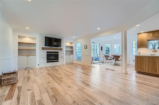 living room featuring light hardwood / wood-style floors, a fireplace, and built in features