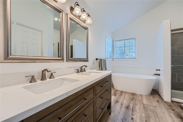 bathroom featuring vanity, a tub to relax in, hardwood / wood-style floors, and vaulted ceiling