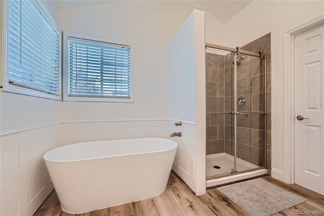 bathroom with wood-type flooring, separate shower and tub, and vaulted ceiling