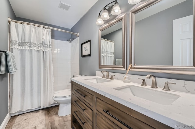 full bathroom with toilet, hardwood / wood-style flooring, vanity, and shower / tub combo