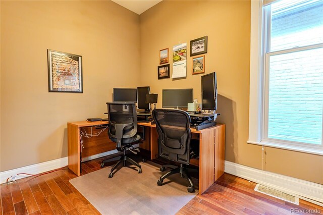 home office featuring baseboards, wood finished floors, and visible vents