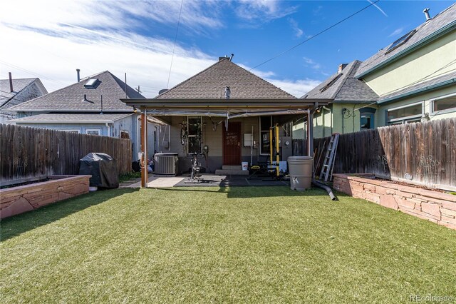 back of property with central AC, a fenced backyard, a shingled roof, a patio area, and a yard