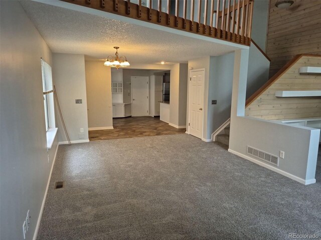 2238 S Nile Ct, Aurora, CO 80014 - unfurnished living room with a chandelier, stairs, carpet floors, baseboards, and a textured ceiling