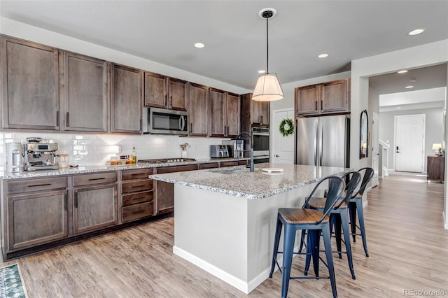 4840 Point Mesa St, Castle Rock, CO 80108 - kitchen with stainless steel appliances, light wood-style flooring, a breakfast bar area, backsplash, and recessed lighting