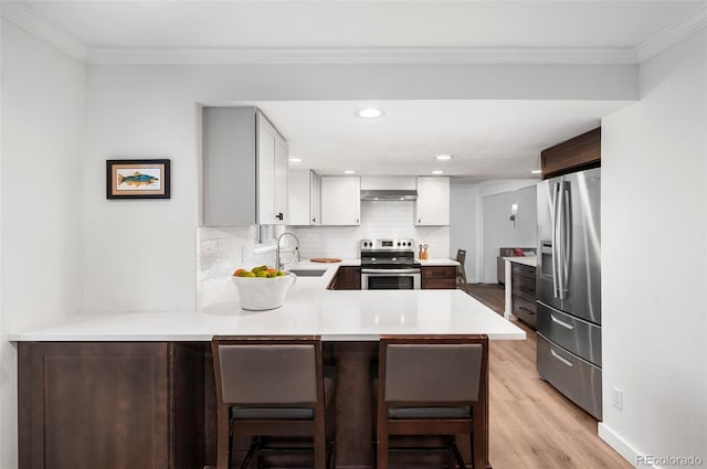 kitchen with kitchen peninsula, appliances with stainless steel finishes, sink, white cabinets, and a breakfast bar area