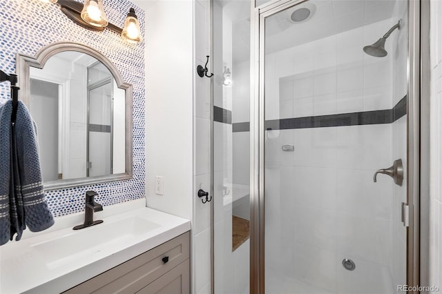 bathroom with vanity, a shower with door, and backsplash