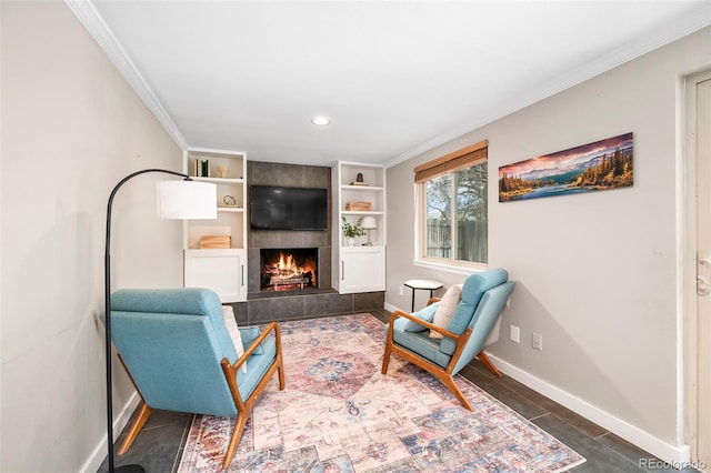 living area featuring a tile fireplace, built in shelves, and crown molding