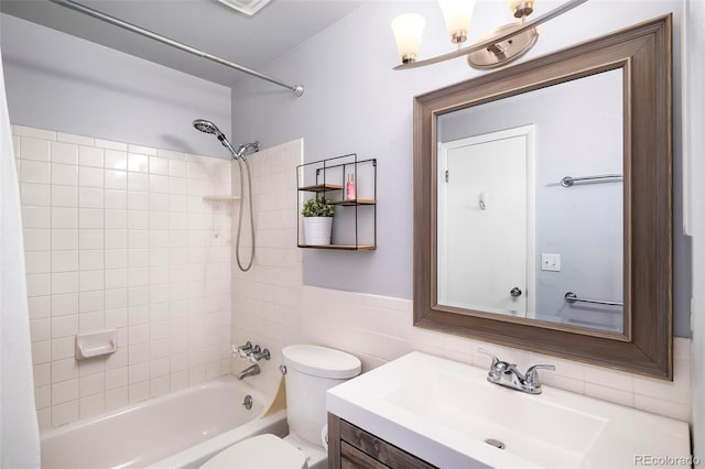 full bathroom featuring vanity, toilet, tile walls, and tiled shower / bath combo