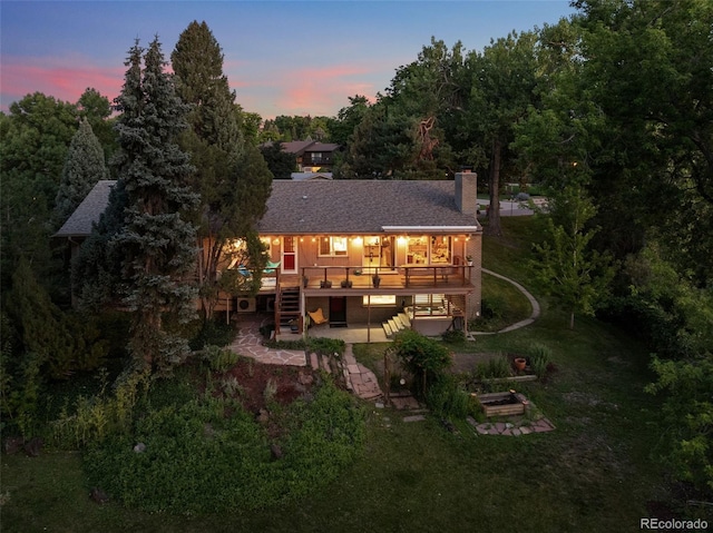 3 Twilight Dr, Wheat Ridge, CO 80215 - back of property at dusk featuring stairs, a patio, a wooden deck, a chimney, and a yard
