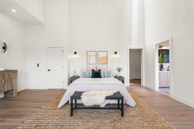 2289 Hiwan Dr, Evergreen, CO 80439 - bedroom featuring a high ceiling, wood finished floors, a baseboard radiator, and ensuite bathroom