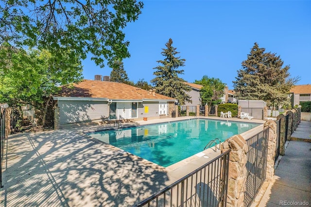 community pool featuring fence and a patio