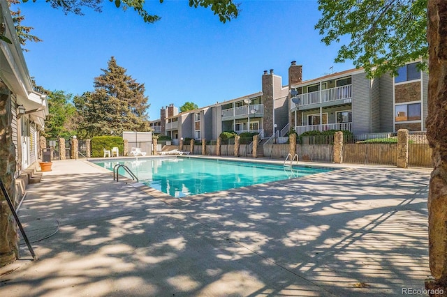 community pool with fence and a patio area