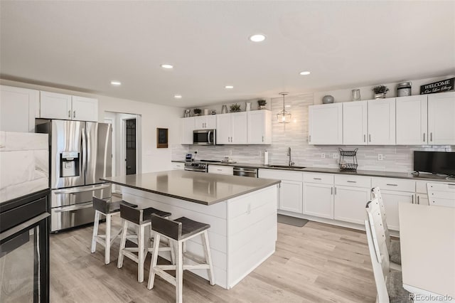 6187 Wescroft Ave, Castle Rock, CO 80104 - kitchen featuring stainless steel appliances, a sink, dark countertops, a breakfast bar area, and light wood-style flooring