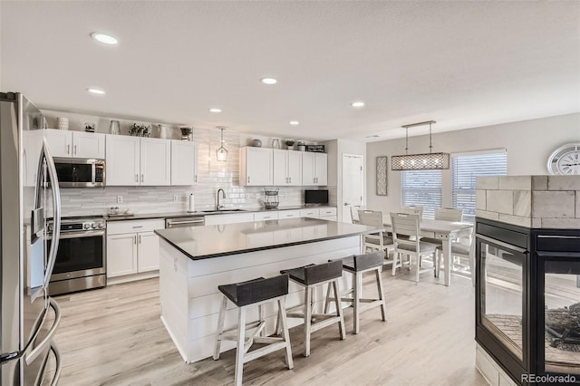 6187 Wescroft Ave, Castle Rock, CO 80104 - kitchen featuring stainless steel appliances, a sink, a breakfast bar, light wood-type flooring, and recessed lighting
