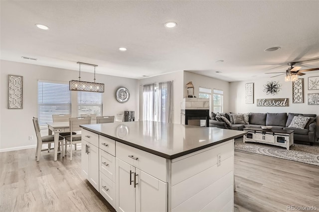 6187 Wescroft Ave, Castle Rock, CO 80104 - kitchen featuring dark countertops, light wood-style flooring, white cabinetry, a center island, and a ceiling fan