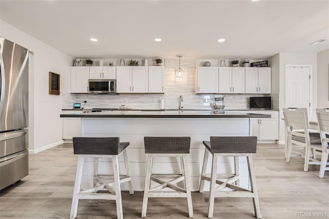 6187 Wescroft Ave, Castle Rock, CO 80104 - kitchen with appliances with stainless steel finishes, a kitchen bar, decorative backsplash, white cabinetry, and dark countertops