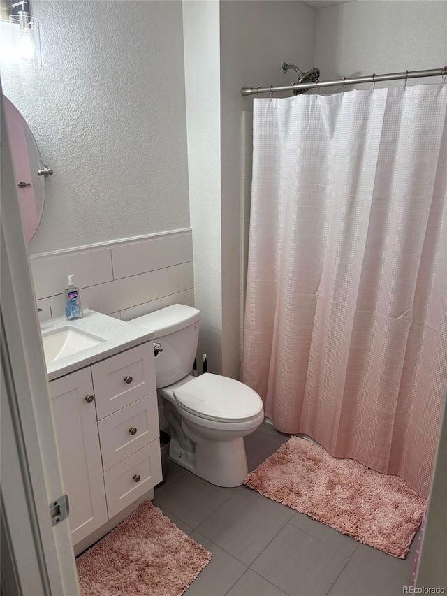 6187 Wescroft Ave, Castle Rock, CO 80104 - bathroom with tile patterned floors, tile walls, wainscoting, toilet, and vanity