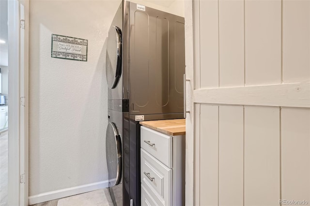 6187 Wescroft Ave, Castle Rock, CO 80104 - washroom with stacked washer / drying machine, a textured wall, and cabinet space