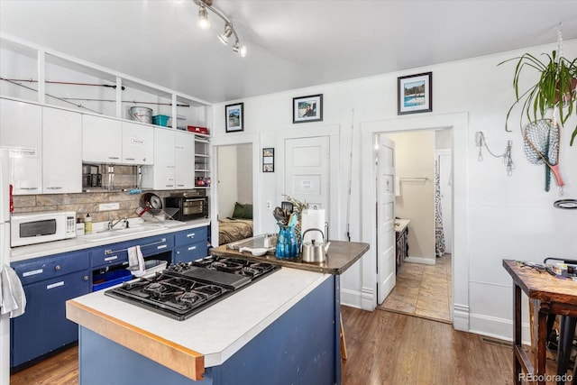 kitchen with a center island, white cabinets, black appliances, blue cabinetry, and dark hardwood / wood-style flooring