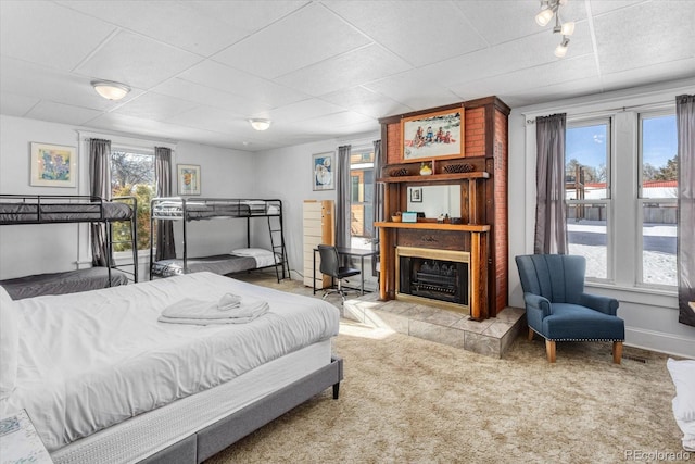 carpeted bedroom featuring a large fireplace and multiple windows