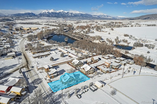 snowy aerial view with a water and mountain view