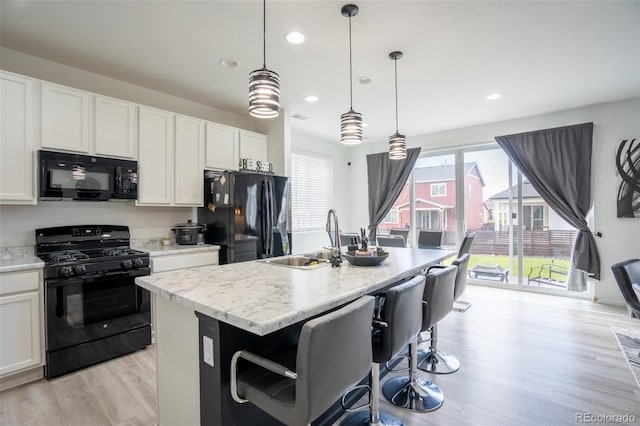26985 E Bayaud Ave, Aurora, CO 80018 - kitchen with black appliances, a sink, a kitchen island with sink, light wood-style flooring, and recessed lighting