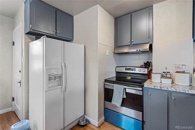 kitchen featuring stainless steel electric stove, gray cabinetry, backsplash, white fridge with ice dispenser, and light wood-type flooring