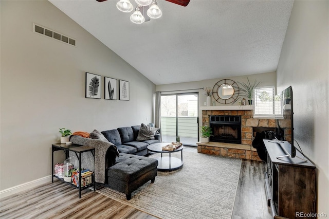 living room with visible vents, a fireplace, light wood-style floors, baseboards, and ceiling fan
