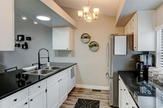 kitchen with white cabinets, baseboards, dark countertops, and a sink
