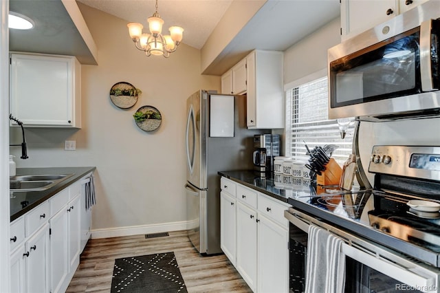 kitchen featuring dark countertops, appliances with stainless steel finishes, baseboards, and white cabinets