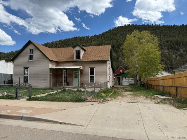 219 Colorado Blvd, Idaho Springs, CO 80452 - view of front of property featuring a wooded view, a fenced front yard, a mountain view, and roof with shingles