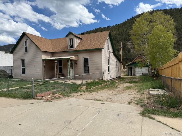 219 Colorado Blvd, Idaho Springs, CO 80452 - view of front facade with dirt driveway, a shingled roof, and a fenced front yard