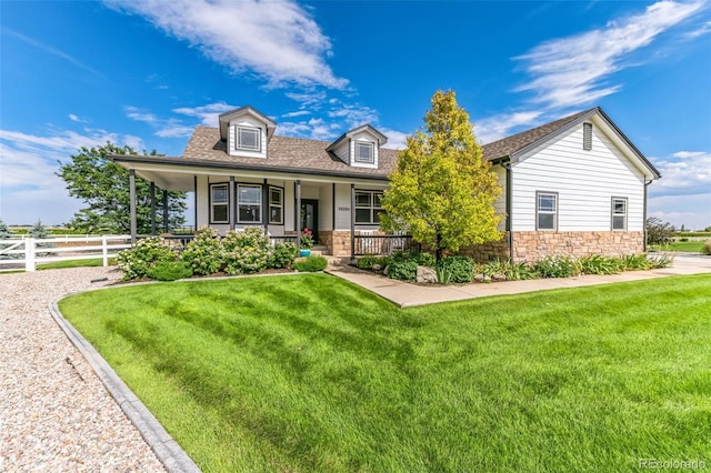 cape cod house with stone siding, a porch, a front lawn, and fence