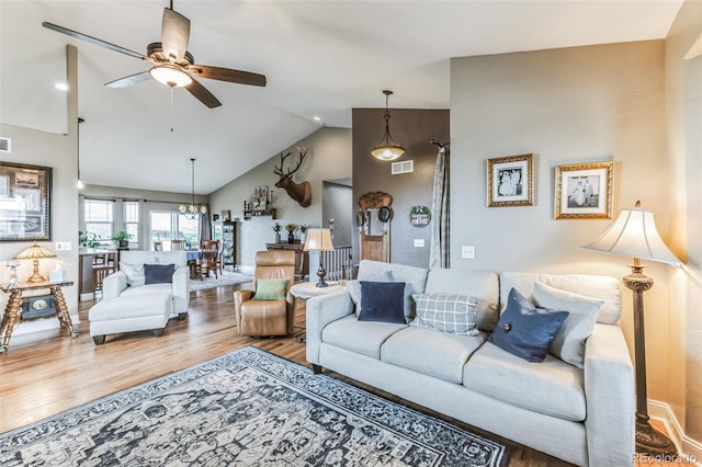 living room featuring visible vents, ceiling fan with notable chandelier, baseboards, and wood finished floors