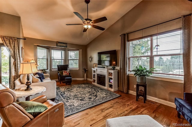 living area featuring a ceiling fan, lofted ceiling, wood finished floors, and a healthy amount of sunlight