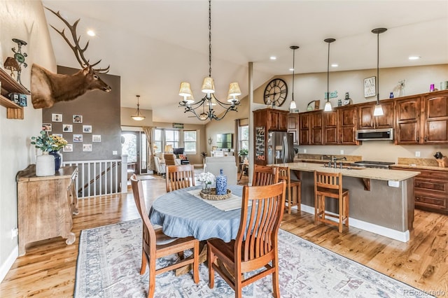 dining space with an inviting chandelier, recessed lighting, light wood-type flooring, and high vaulted ceiling