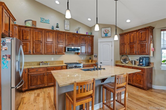 kitchen with a sink, stainless steel appliances, lofted ceiling, and light wood finished floors