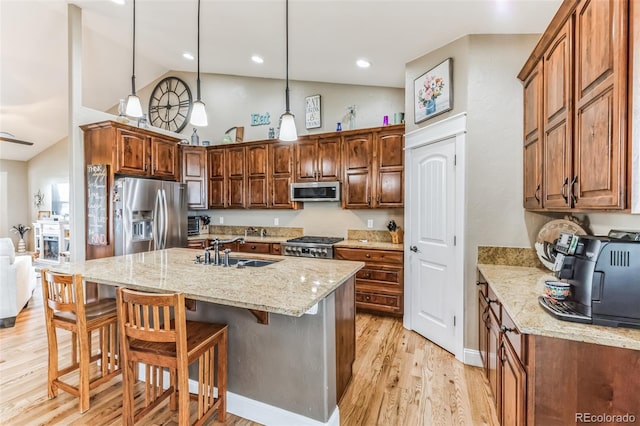 kitchen featuring a sink, light stone counters, light wood-style floors, and stainless steel appliances