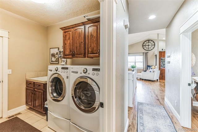 washroom featuring visible vents, light wood-style flooring, cabinet space, separate washer and dryer, and baseboards