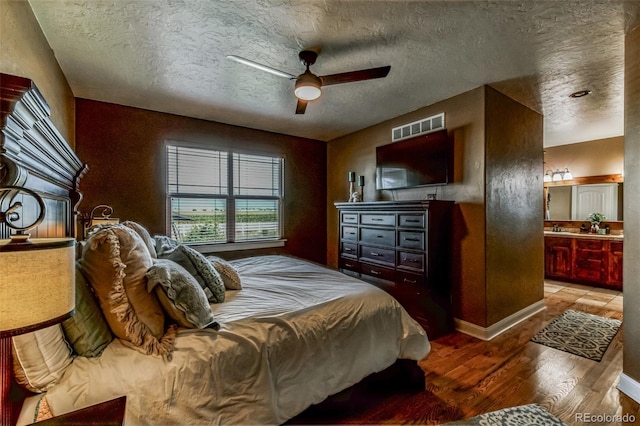 bedroom featuring visible vents, a textured ceiling, a ceiling fan, and wood finished floors