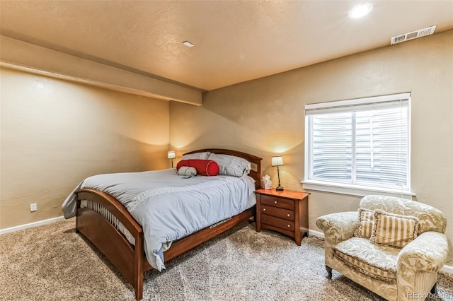 carpeted bedroom featuring visible vents, baseboards, and a textured wall