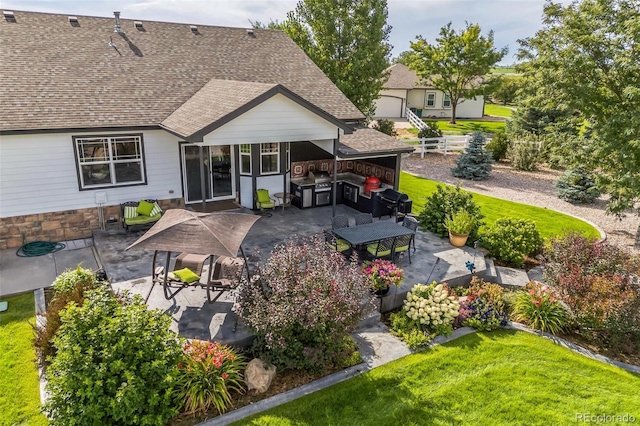 rear view of property featuring a yard, roof with shingles, and a patio area